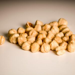 Pile of raw hazelnuts on a white surface, captured in a close-up shot. Ideal for food and nutrition content.